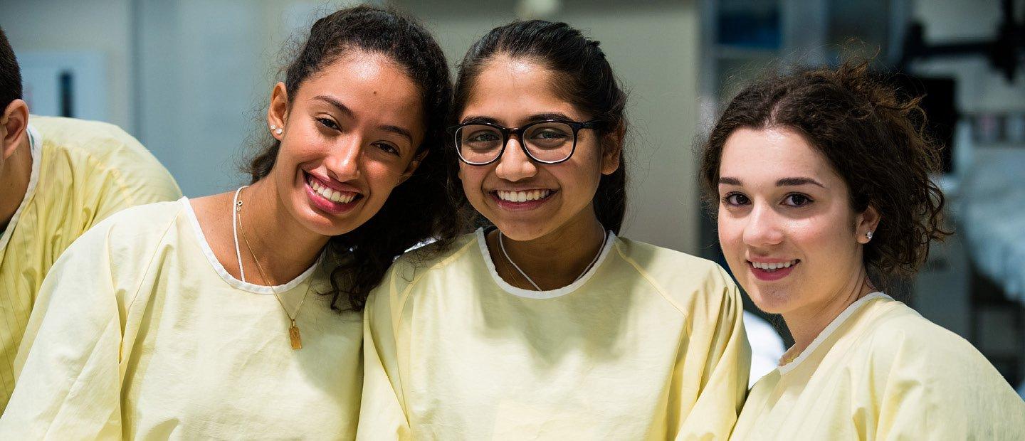 three female students in yellow lab coats